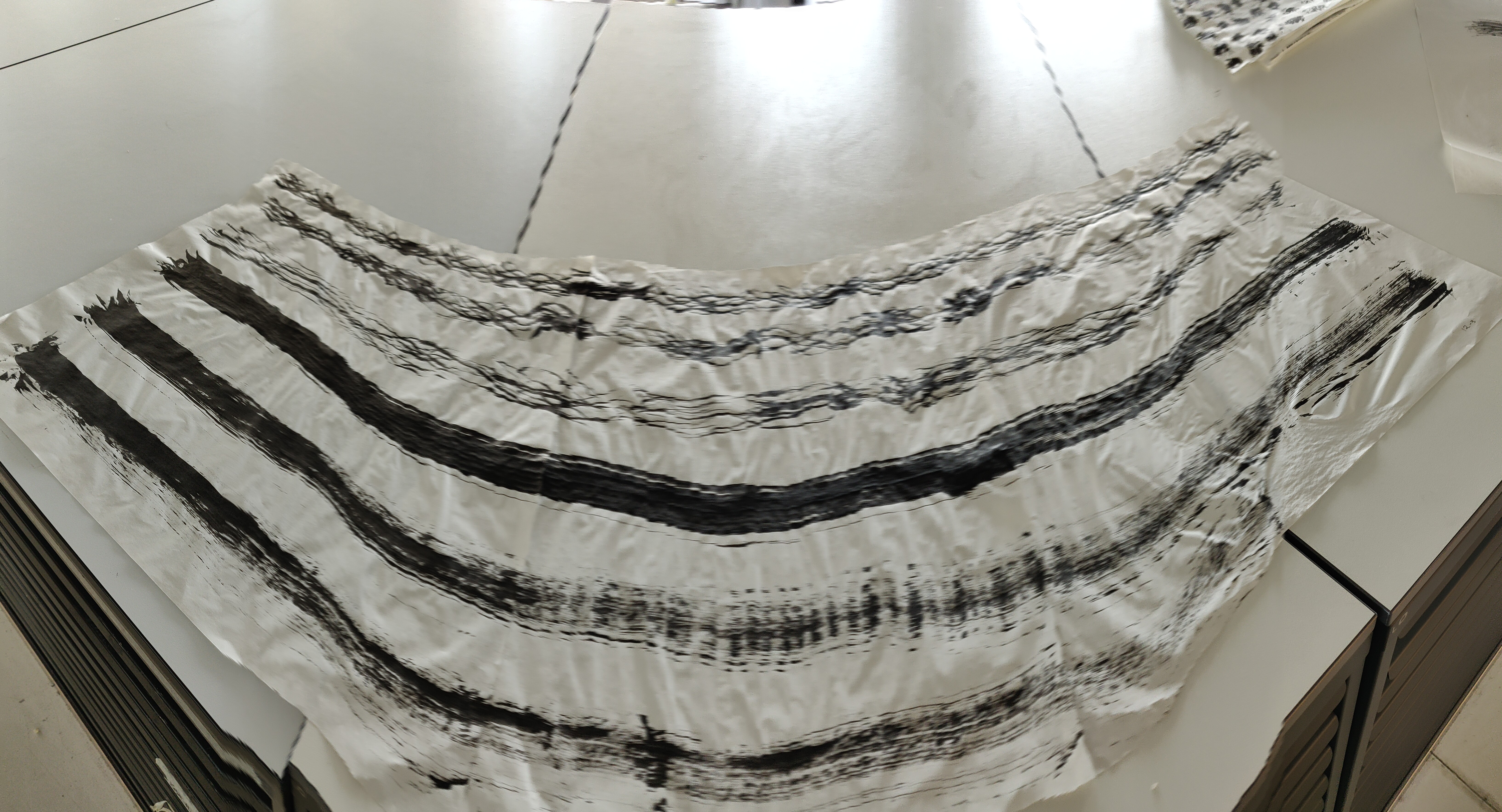 photograph of an abstract drawing, black ink on paper, long lines of black ink fade away as the ink runs out